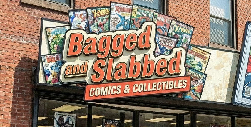 Storefront with 'Bagged and Slabbed Comics & Collectibles' sign and comic books displayed.